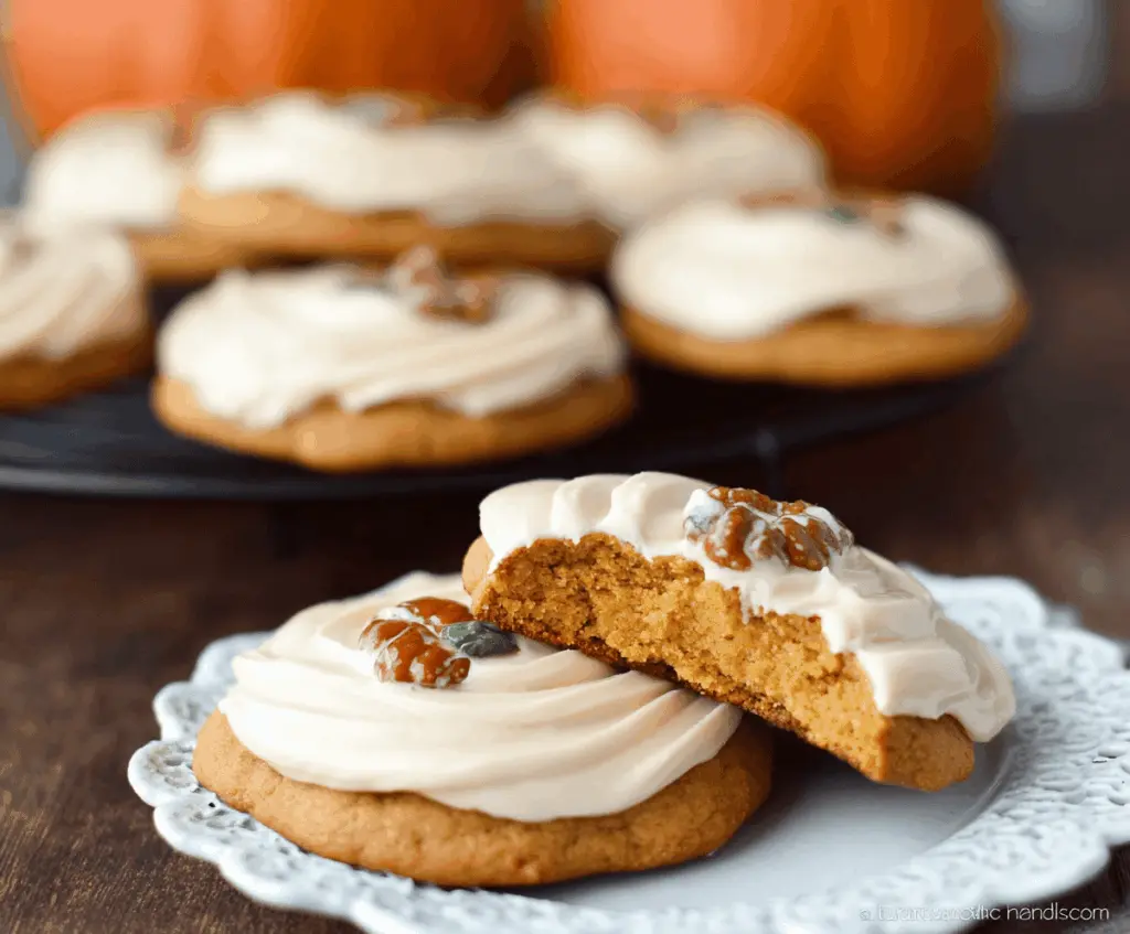 Delicious pumpkin cookies topped with creamy maple cream cheese frosting on a festive plate