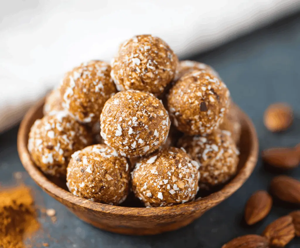 No-Bake Pumpkin Pie Energy Balls topped with crushed nuts and cinnamon on a plate, healthy fall snack, festive dessert bites