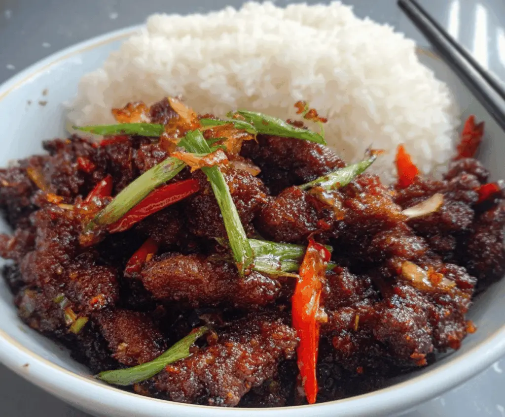 Delicious Crispy Chilli Beef served with vibrant peppers and garnished with fresh herbs.
