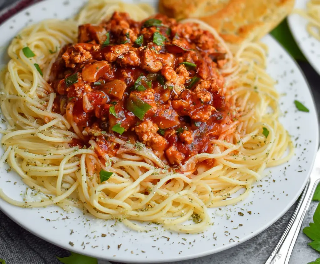 Delicious veggie-loaded ground chicken spaghetti sauce in a bowl with fresh vegetables and herbs.