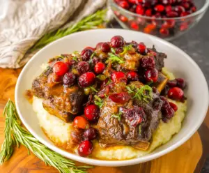 Delicious Crockpot Cranberry Beef Short Ribs served with fresh herbs and vegetables.