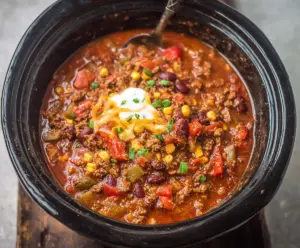 Delicious Crockpot Root Beer Chili served in a bowl with fresh herbs and sour cream.