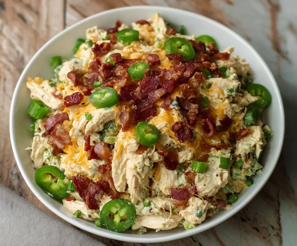 Creamy Jalapeño Popper Chicken Salad with melted cheese and fresh jalapeños in a bowl.