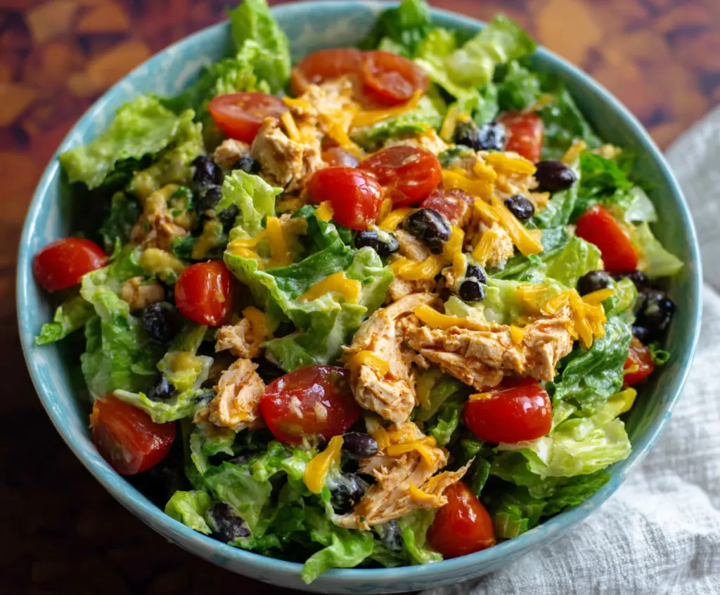 Delicious Taco Chicken Salad in a bowl with fresh vegetables and shredded cheese